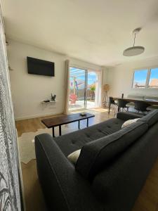 a living room with a couch and a piano at Casa Côme - Maison climatisée - Tout à pied ! in Saint-Vincent-sur-Jard