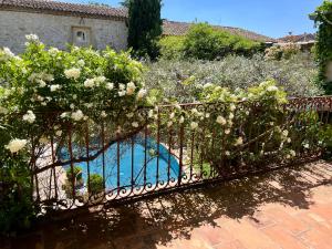 a wrought iron fence with white flowers on it at La Maison Des Autres, piscine chauffée, chambres d'hôtes, proche d'Uzès, Nîmes, Pont du Gard, Alès in Saint-Géniès-de-Malgoirès