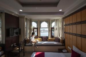 ウダイプールにあるHide-In Udaipur - A Lake View Boutique hotelの窓のある部屋のベッドに座っている人 +73枚の写真