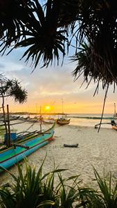 a group of boats on the beach at sunset at Ayaan Beach Home in Dodanduwa