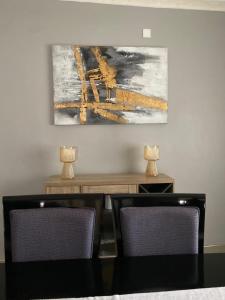 a dining room with two chairs and a painting on the wall at The Stone Duplex Apartment House 1 in Lilongwe