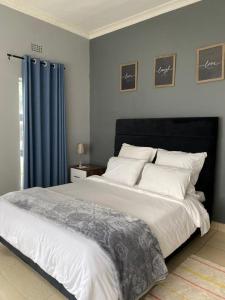 a bedroom with a large white bed with blue curtains at The Stone Duplex Apartment House 1 in Lilongwe