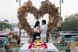 ウダイプールにあるHide-In Udaipur - A Lake View Boutique hotelのケーキが置かれたテーブルの前に立つカップル