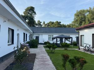 a courtyard of a white house with a garden at Pensjonat Eden Apartament 5 in Borne Sulinowo