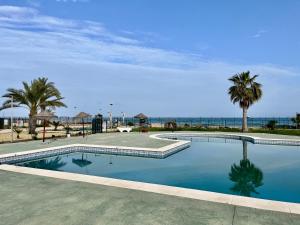 a swimming pool with palm trees and the ocean at Vera Naked in Vera