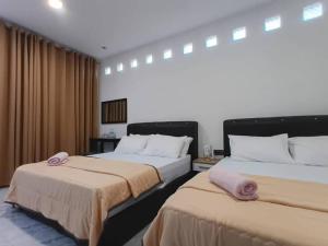 two beds in a hotel room with curtains at Losd Village Cottage in Kuala Perlis