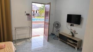 a room with a television and a door with a fan at Losd Village Cottage in Kuala Perlis
