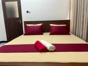 a bed with two red and white towels on it at Wagon Inns anuradhapura in Anuradhapura