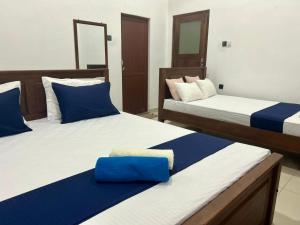 a bedroom with two beds with blue and white sheets at Wagon Inns anuradhapura in Anuradhapura +36 photos
