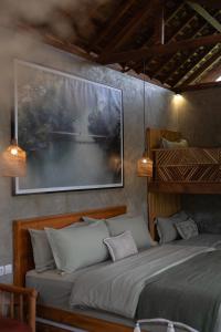 a bedroom with a bed and a painting on the wall at The Salty Jungle in Cijulang Nusawiru Airport