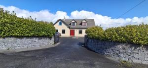 a white house with a red door and a stone wall at Aira Lodge Accommodation in Kinvara