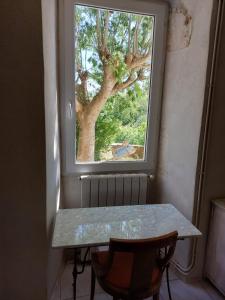 a table in front of a window with a tree at Le Gite in Labastide-de-Virac