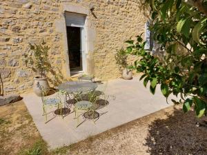 a patio with a table and chairs in front of a building at Le Gite in Labastide-de-Virac