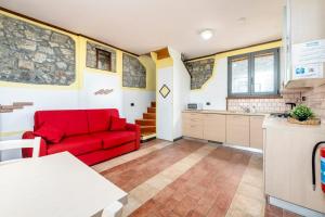 a living room with a red couch and a kitchen at Appartamenti Residence Montebello, relax con giardino e piscina in Bolano