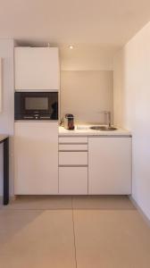 a white kitchen with a microwave and a sink at Le Semiramis l Central & Views l Shellter Rentals in Saint-Tropez