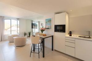a kitchen with white cabinets and a table and chairs at Le Semiramis l Central & Views l Shellter Rentals in Saint-Tropez