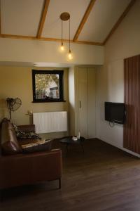 a living room with a couch and a flat screen tv at B&B de Lytse Geast in Tietjerk