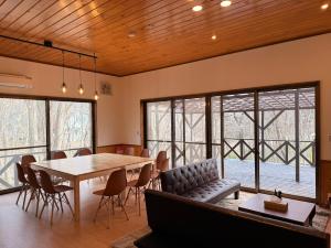 a dining room with a table and chairs and windows at BBQ屋根付き大型ウッドデッキ川のせせらぎを聴きながら贅沢時間ペット同伴OK森と音に癒されるコテージ Rill in Nasu