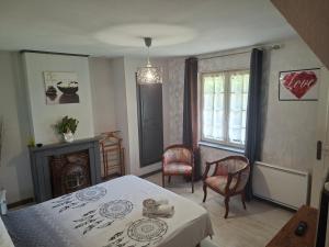 a bedroom with a bed and two chairs and a fireplace at La Ferme aux Canards in Sassetot-le-Mauconduit
