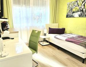 a bedroom with a bed and a desk and a window at Pension Bunz in Kelsterbach
