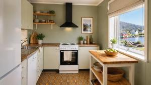a kitchen with a stove and a table and a window at KB - Waterfront Villa Sørvågen in Moskenes