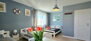 a living room with blue walls and red flowers at Pokoje Syrenka by TriApart in Stegna
