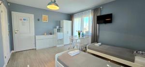 a bedroom with a bed and a table and a kitchen at Pokoje Syrenka by TriApart in Stegna
