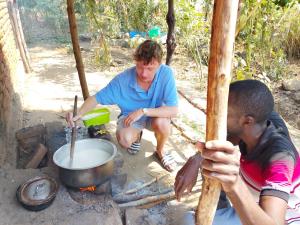 a man and a woman cooking over a fire at TWESA Community Guest House in Chibotero