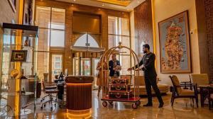 two people standing in a lobby with a luggage cart at Heritage Inn Hotel Apartments in Al Wakrah