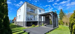a white house with a wooden deck in the yard at Pokoje Syrenka by TriApart in Stegna
