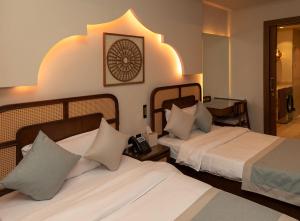 a hotel room with two beds and a clock on the wall at Heritage Inn Hotel Apartments in Al Wakrah +41 photos