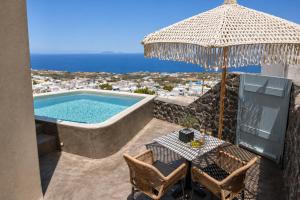 a patio with a table and an umbrella and a swimming pool at Panthea Suite Santorini - Private pool in Vourvoúlos
