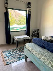 a room with two beds and a window and a chair at Stay Maasa Resort in Shivpuri