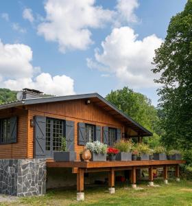a log cabin with a wooden deck and flowers at Chambre & grande Terrasse Privées, Vue Montagne - Chalet Bella Rosa in Argein