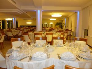 a dining room with white tables and chairs with glasses at Hotel Terme Marine Leopoldo II TERME & SPA in Marina di Grosseto