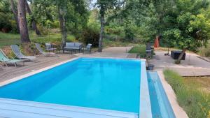 a blue swimming pool with chairs and a patio at Maison des Pins in Salavas