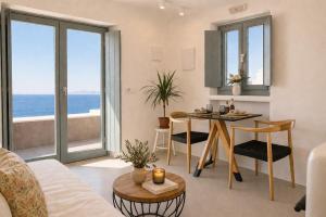 a living room with a table and a view of the ocean at Panthea Suite Santorini - Private pool in Vourvoúlos