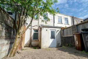 a white house with a garage and a tree at 3 Bedroom House in Rishton by Eason Stays, Great Location Near Shops & Transport in Rishton