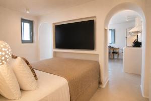 a bedroom with a bed and a flat screen tv at Panthea Suite Santorini - Private pool in Vourvoúlos