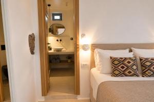 a bedroom with a bed with a mirror and a sink at Panthea Suite Santorini - Private pool in Vourvoúlos +13 photos
