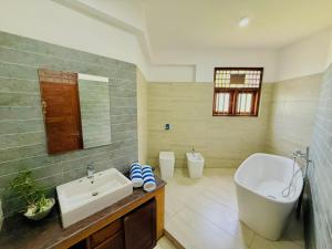a bathroom with a sink and a tub and a toilet at Sky Palace Hikka in Hikkaduwa