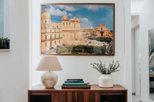 a painting of a building on a wall next to a table with a lamp at Saffi Suites in Noto