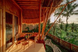 a porch of a house with a table and chairs at Bambu Teras Viewpoint in Karangasem