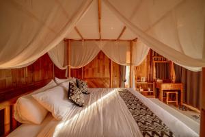 a bedroom with a large white bed with curtains at Bambu Teras Viewpoint in Karangasem