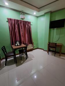 a room with a table and chairs and a television at JMM Guest House in Panglao Island