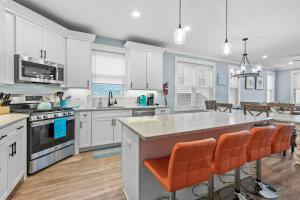 a kitchen with white cabinets and orange bar stools at Cozy Shoregri La! - Beach block! in Seaside Heights