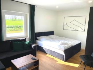 a bedroom with a bed and a couch and a window at Ferienwohnung Bahnblick - Stilvoll in bester Lage - als Wohnung oder Haus in Olbersdorf