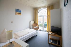 a bedroom with a bed and a tv and a window at Hotel Schlosshof Dolgesheim in Dolgesheim