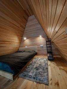a bed in a wooden room with a ladder in it at A-frame будиночок in Staraya Guta