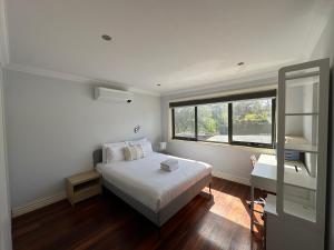 a white bedroom with a bed and a window at Shine House in Balwyn North +30 photos